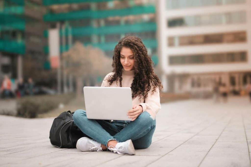 Étudiante utilisant son ordinateur portable à l'extérieur du bâtiment de l'université