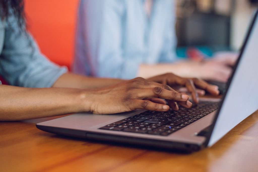 Mãos a escrever num computador portátil