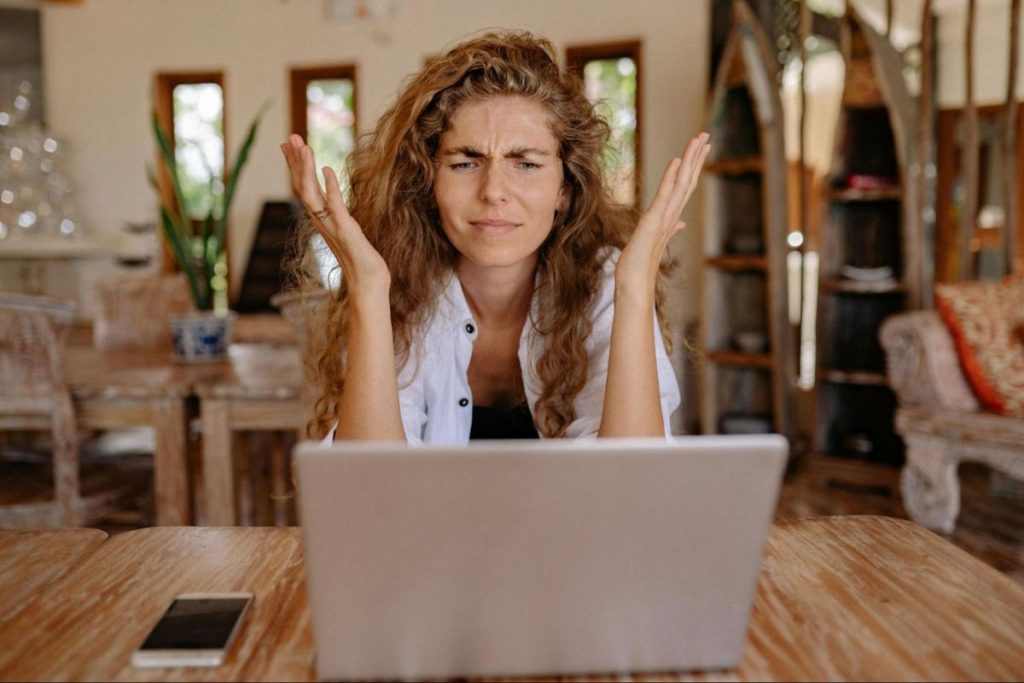 Mulher com ar confuso em frente ao seu computador portátil