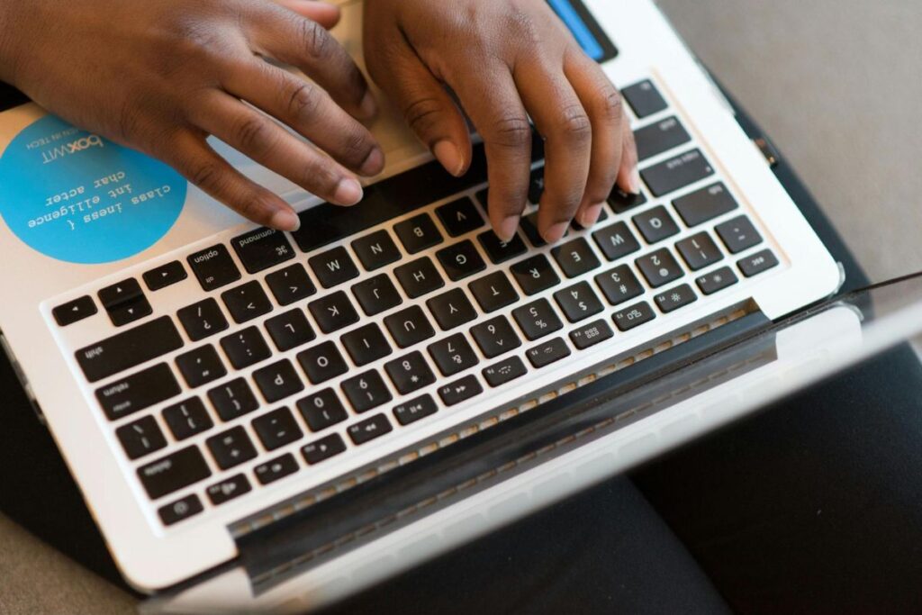 Primer plano de manos masculinas afroamericanas escribiendo en el teclado de un portátil