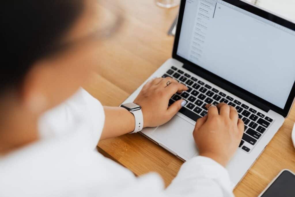 Close-up image of a hand typing on a white laptop keyboard