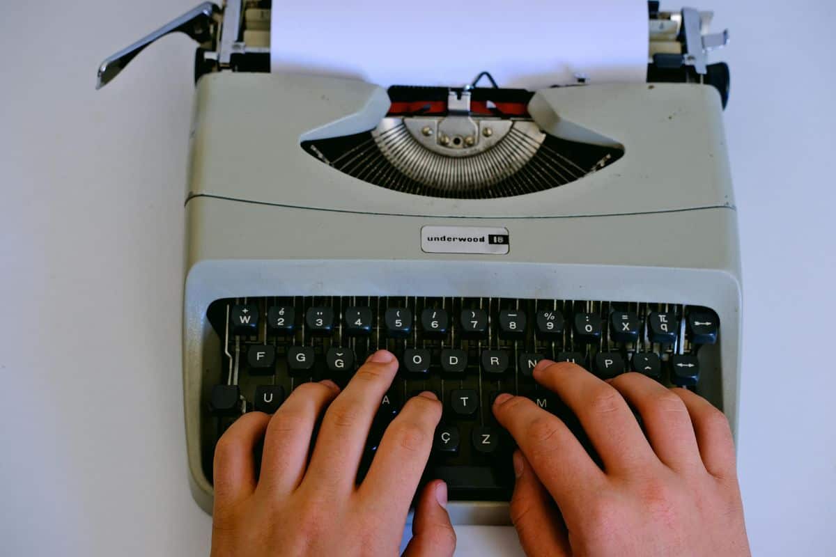 Mãos a dactilografar numa máquina de escrever Underwood antiga