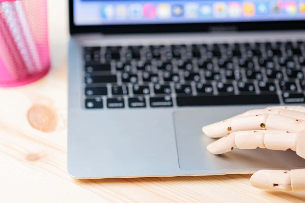 Robotic arm using laptop on a wooden table artificial intelligence