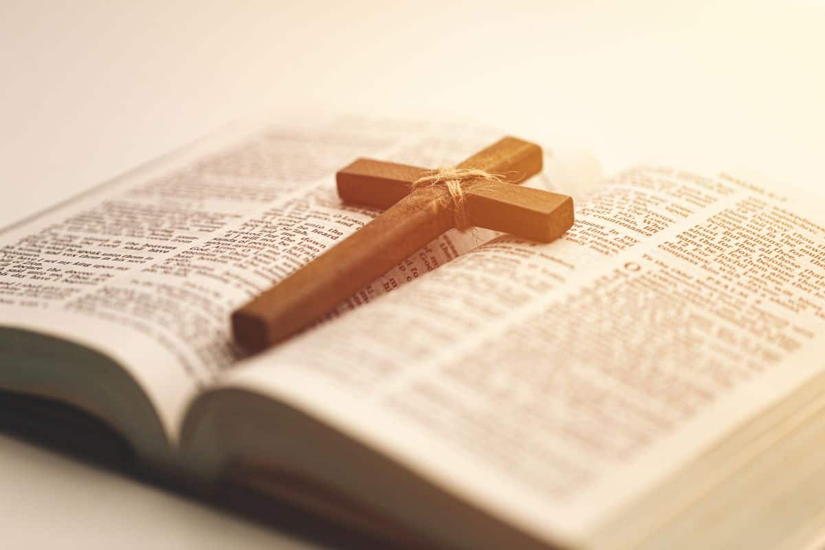 Wooden christian cross on an open bible with warm sunlight