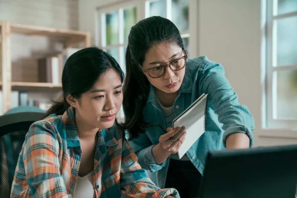 Two asian women colleagues working together with laptop