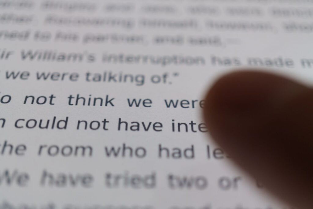 Guida alla frase topica: Definizione, tipi ed esempi 4 Human finger pointing at text on ebook reader screen close up