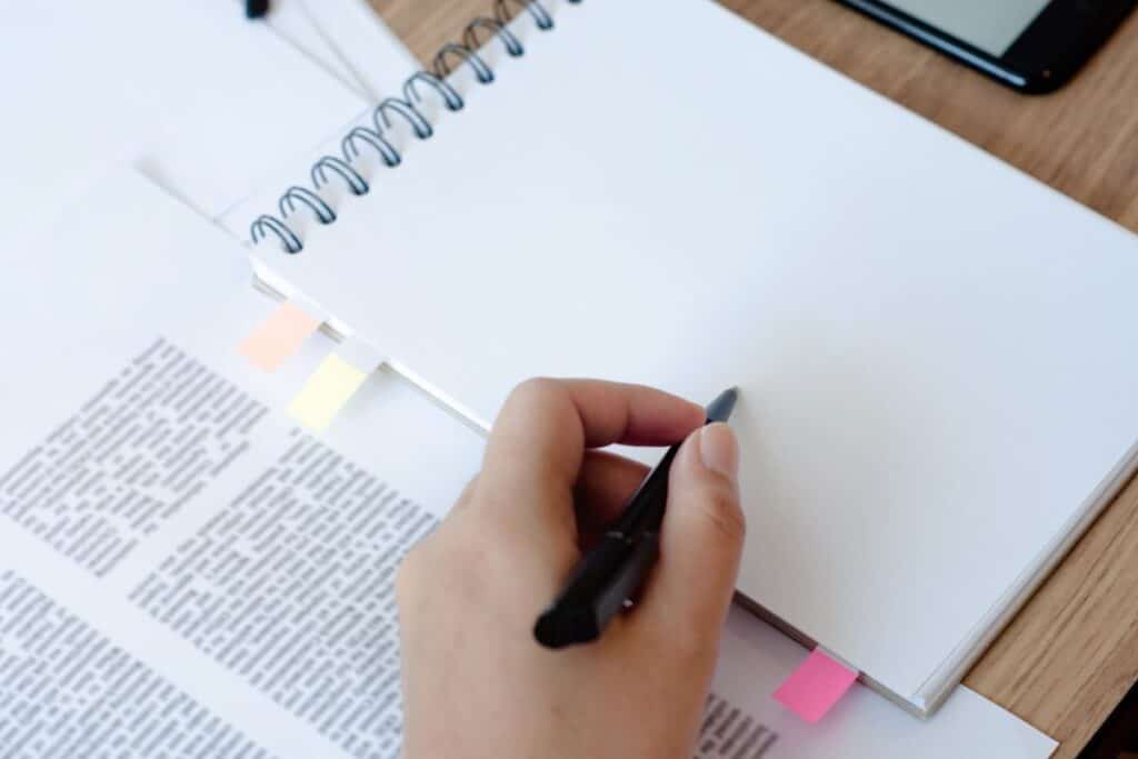 Cropped hand with book and pen on table