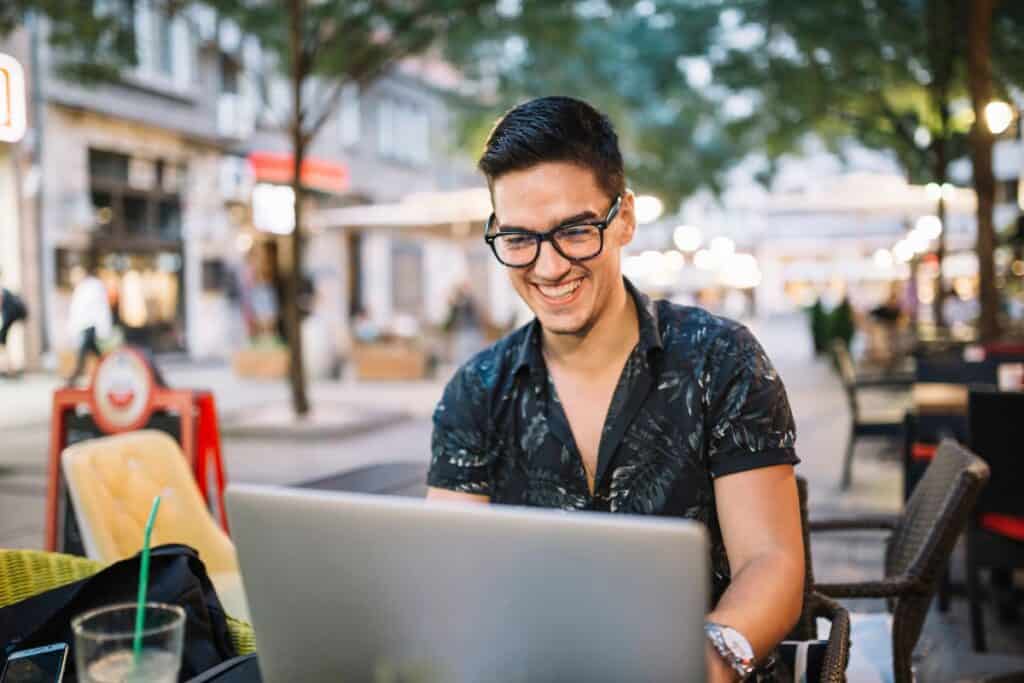 Smiling man working on laptop in caf
