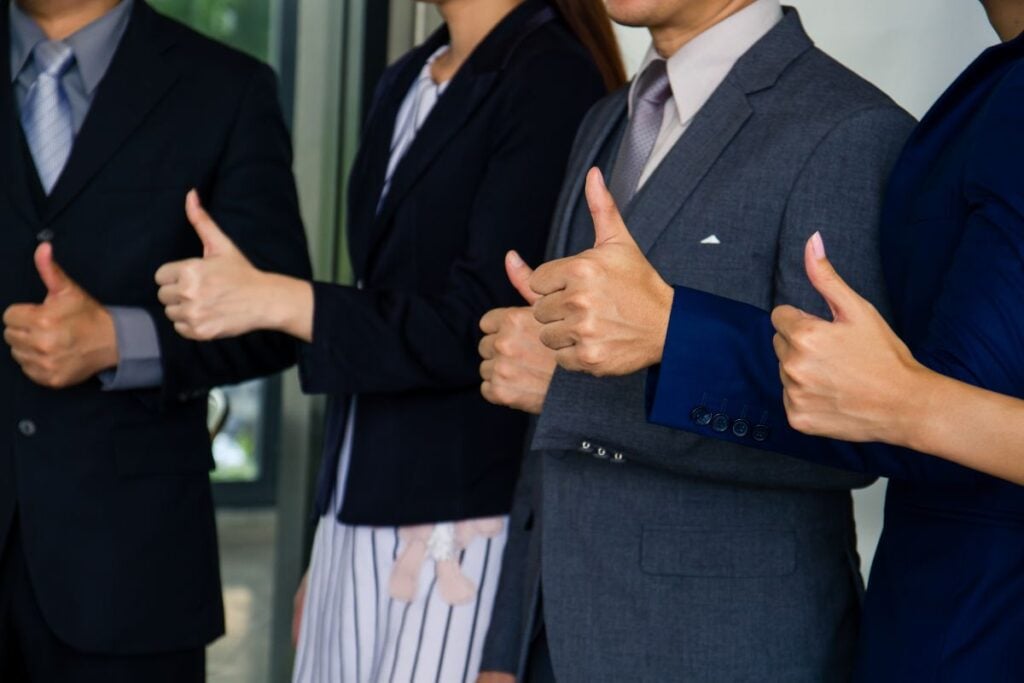 Business people showing thumbs up sign