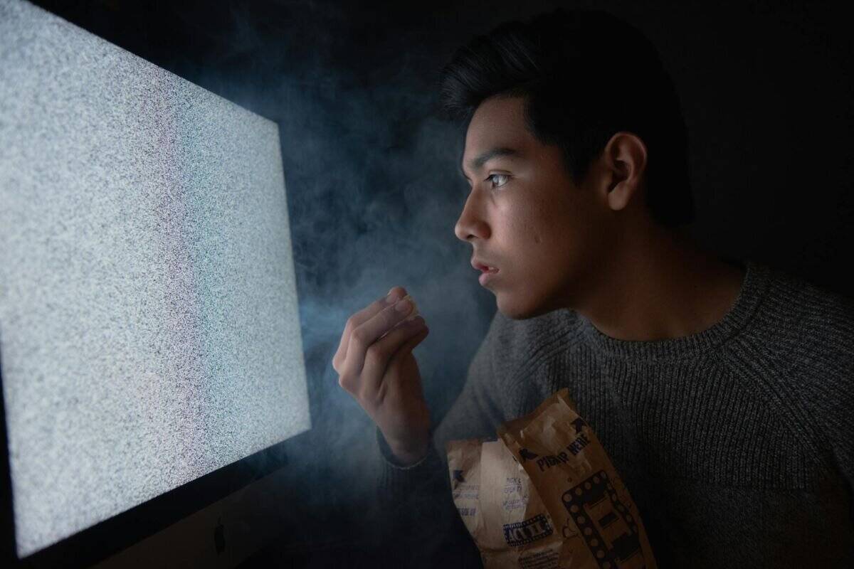 Stockbild av en man som äter popcorn medan han tittar på en suddig skärm