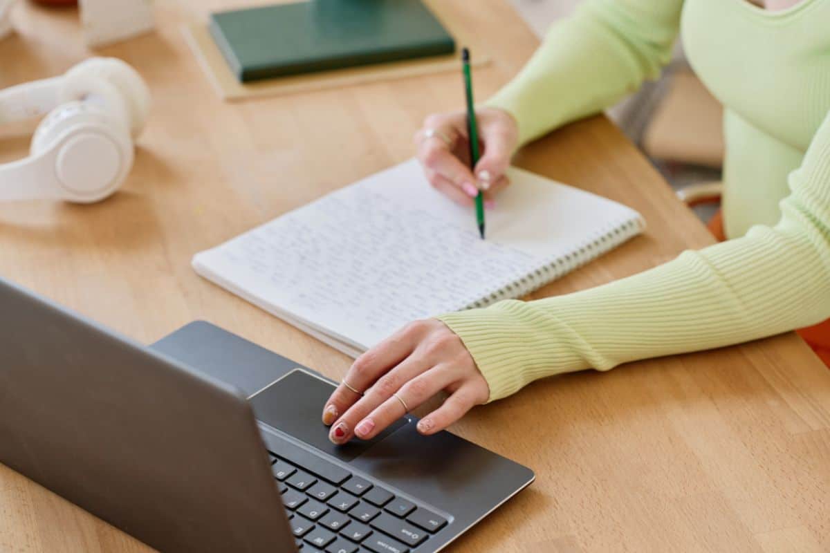 Young female student making notes in copybook