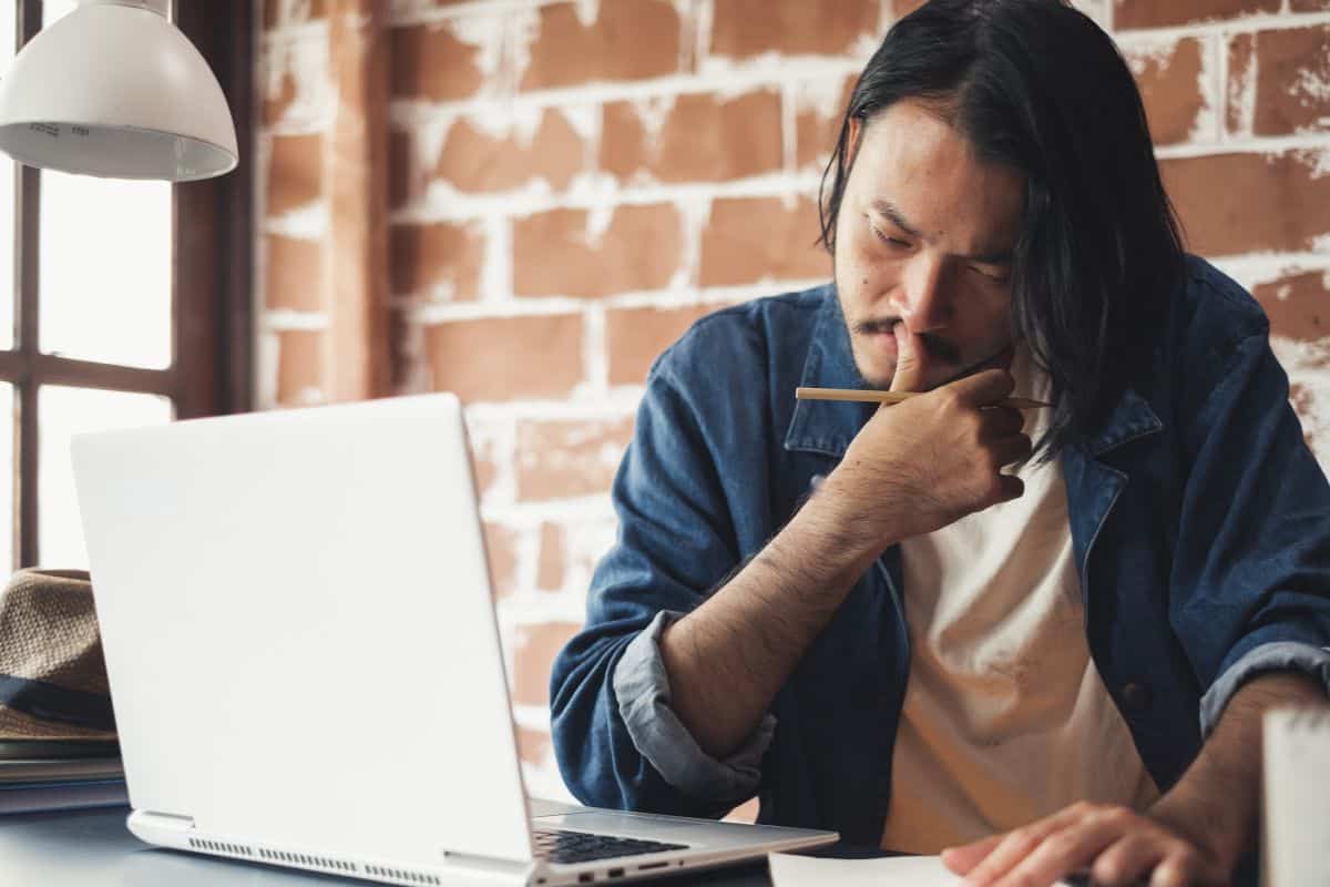 Young asian man thinking and working on laptop for business creative