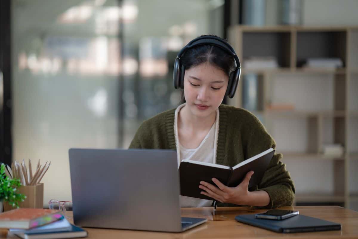 Asian women wearing headphones study online watch webinar podcasts