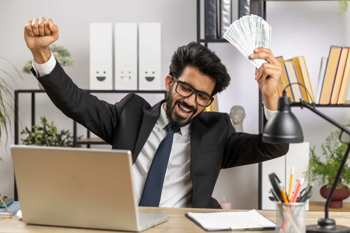 Indian businessman winner holding fan of dollar money cash