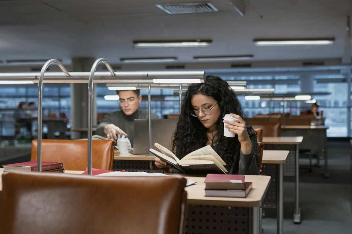 Una donna in biblioteca con in mano un libro e una tazza di caffè