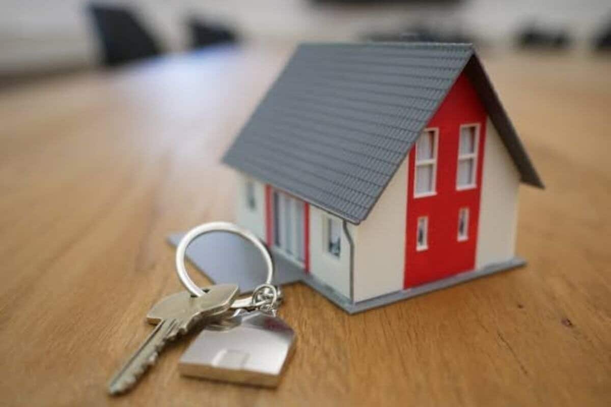 Image de stock d'une maison miniature à côté d'une clé symbolisant l'immobilier