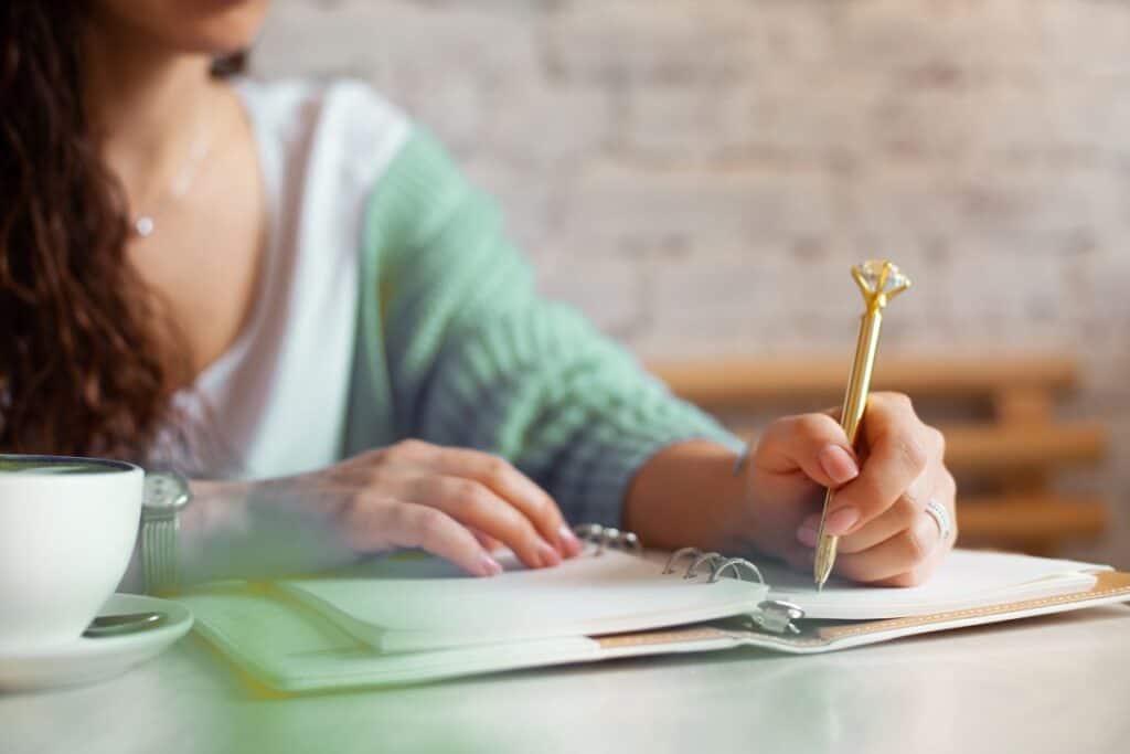 Well groomed woman hand holding gold pen and writing notes 