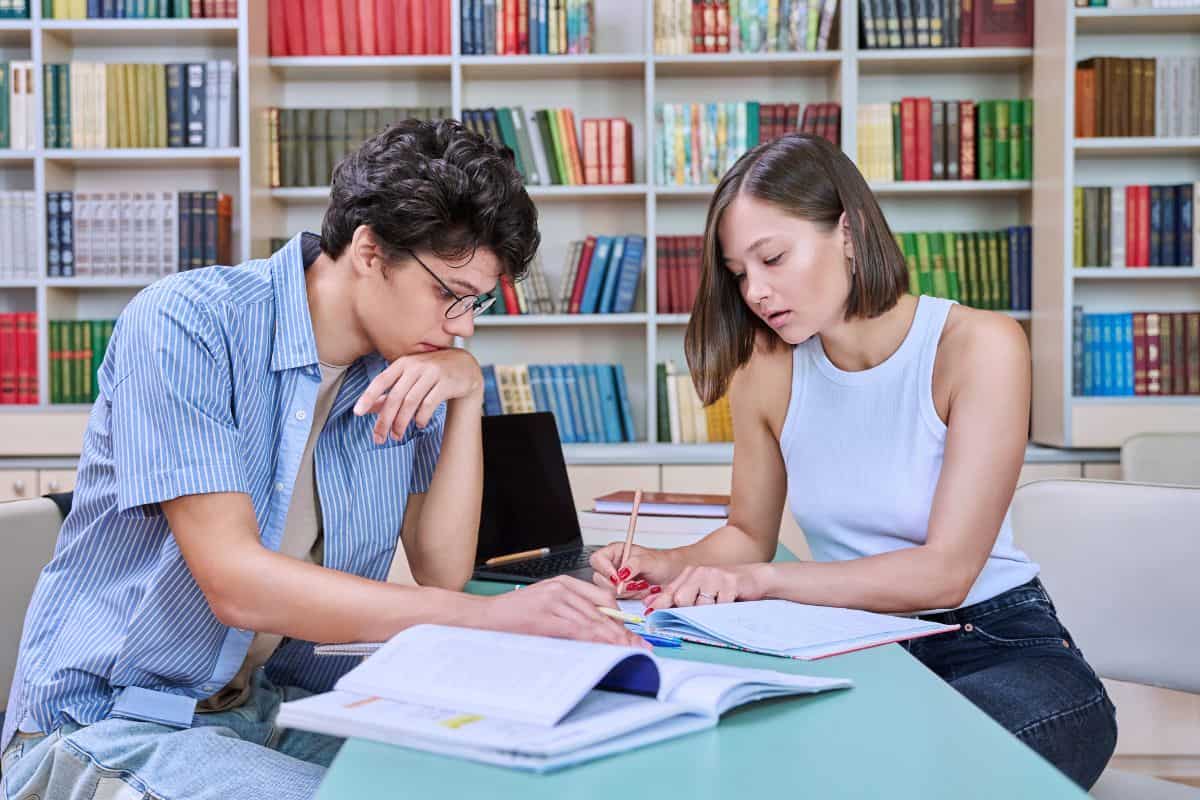 Two students sitting in college library studying preparing for exams