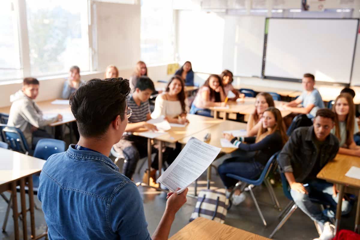 Rear view of male high school teacher standing at front of class