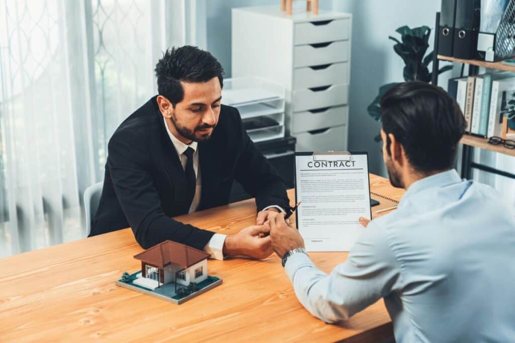 A man in a suit is sitting at a table with a sign