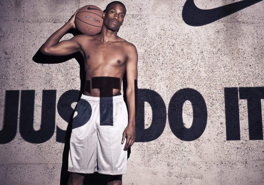 En mand holder en bold med Nike-logoet og sloganet 'Just Do It' på en fremtrædende plads.