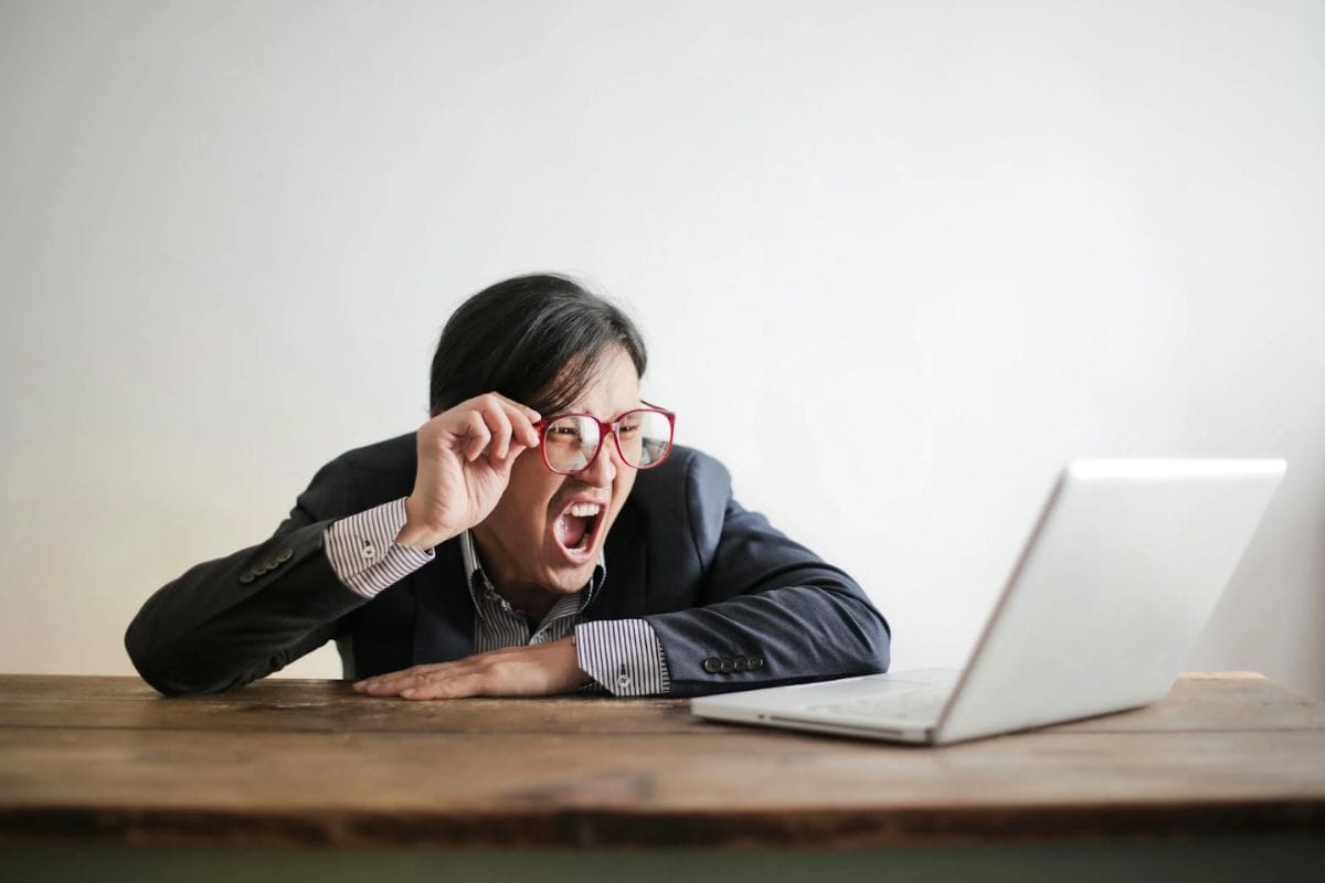 A stock image of a man looking shocked while using a laptop