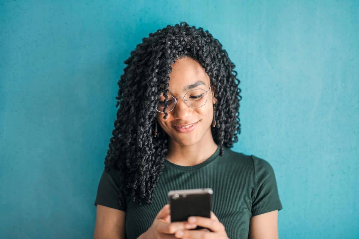 A Black woman looking at her phone with a focused expression.