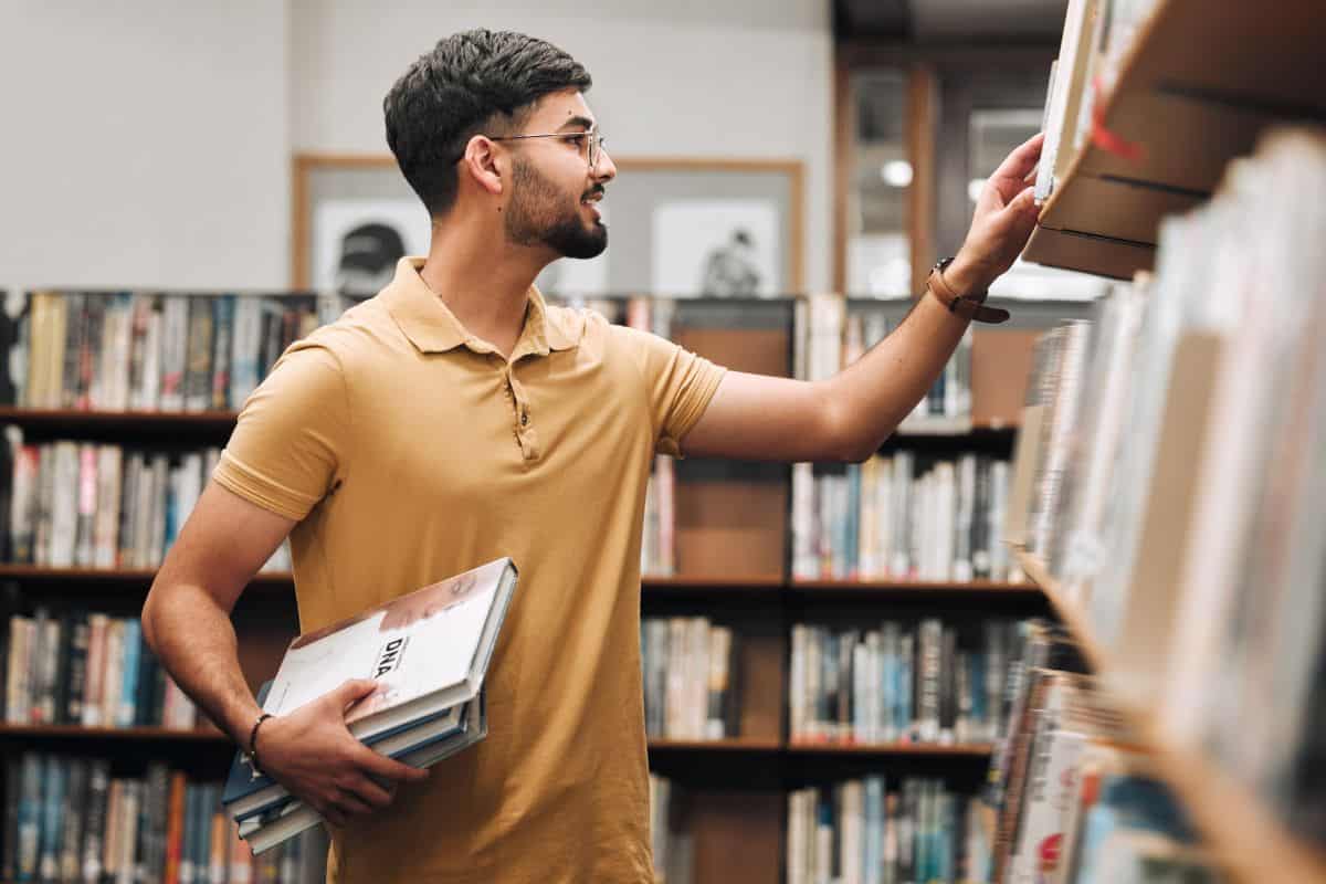 Student man search bookshelf and library for reading information