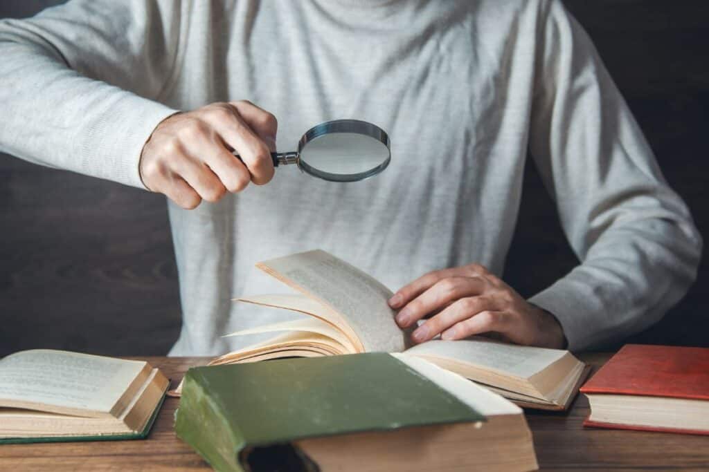 Man hand magnifier and books on the table