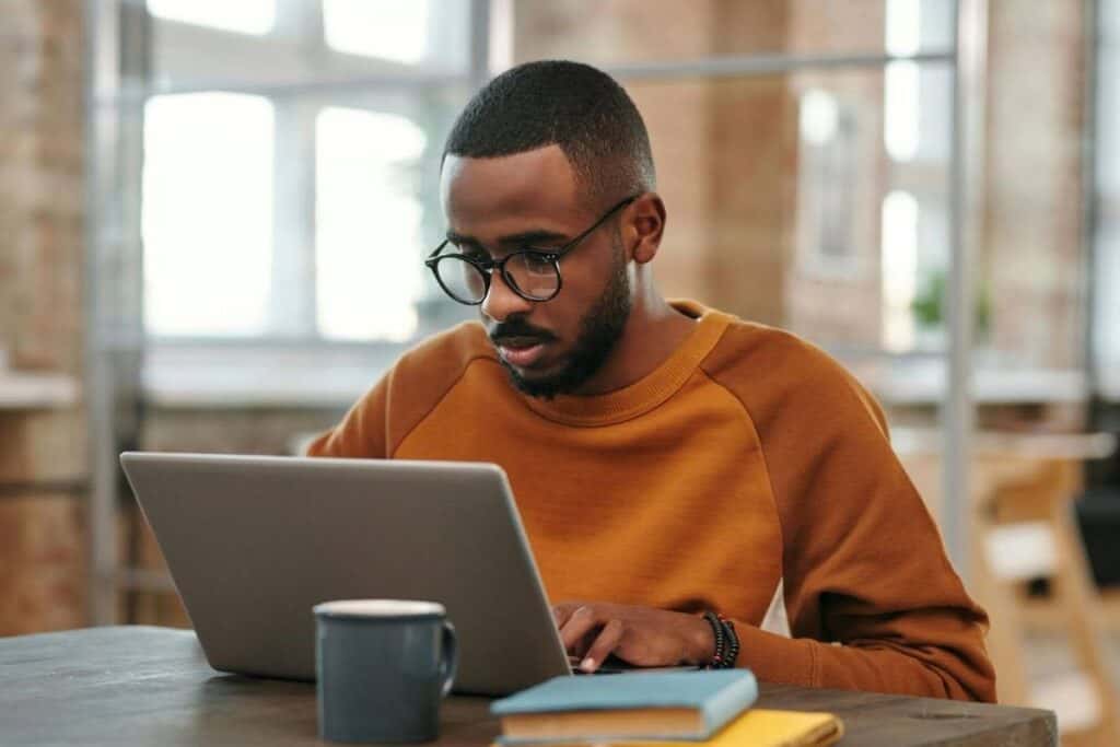 A Man in Sweater Using Laptop