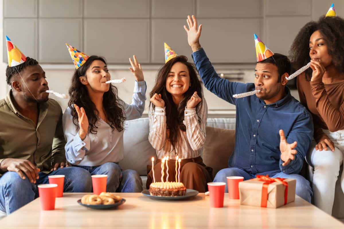 Diverse friends in festive hats making birthday wish indoor
