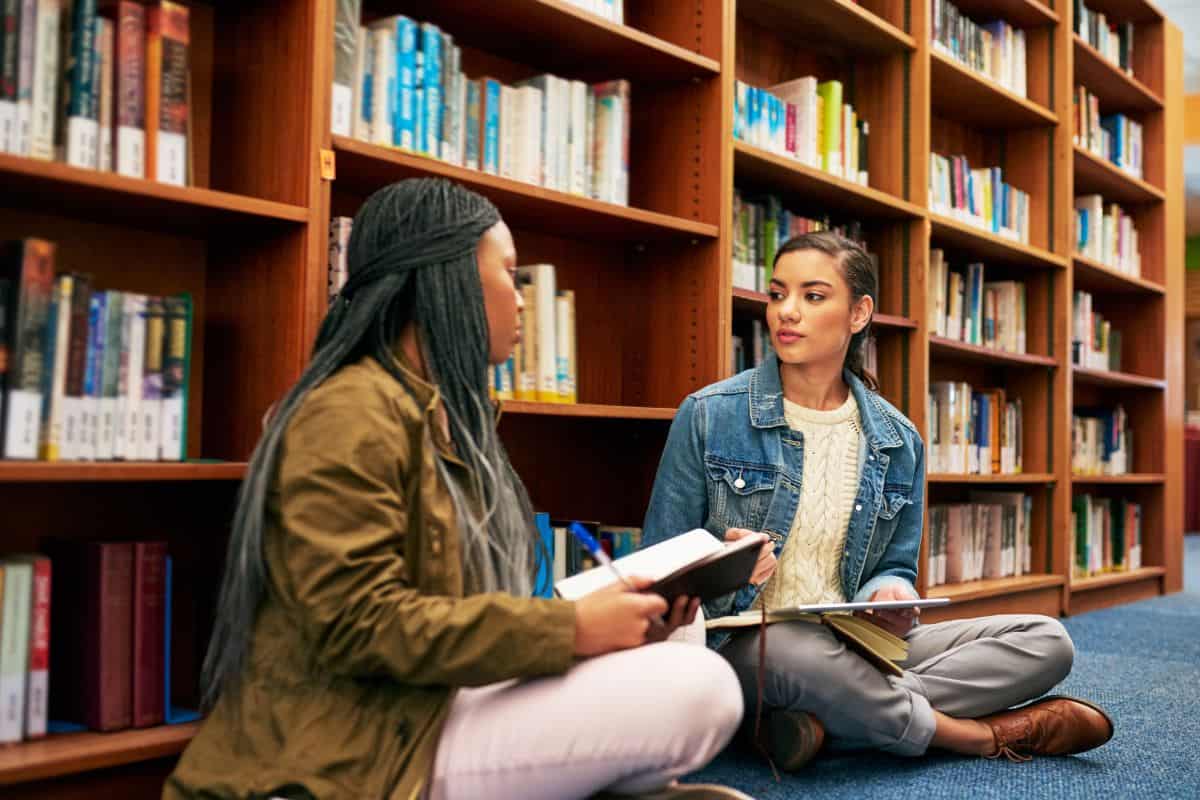 Women tech and books in library for studying research