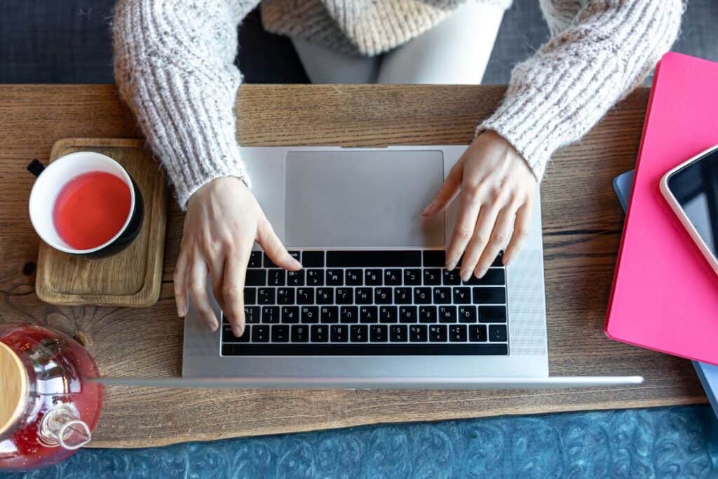 Ottimizzazione dei contenuti AI: Come usare l'intelligenza artificiale per aumentare la SEO 5 Woman working on a laptop in a cafe with a cup of tea top view