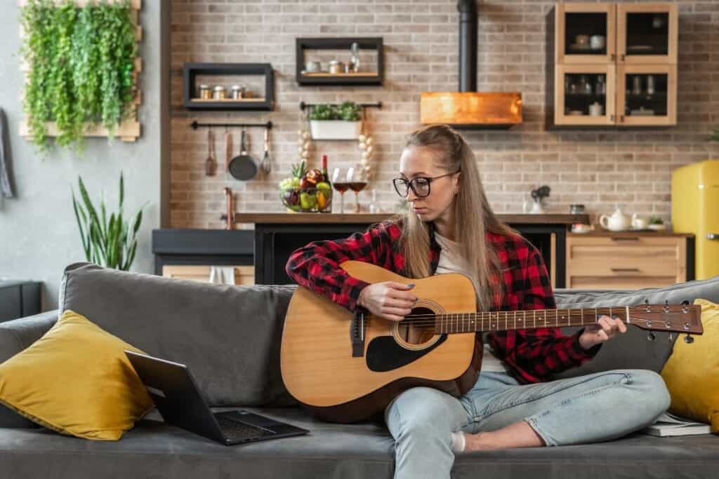 Young woman is learning to play the guitar