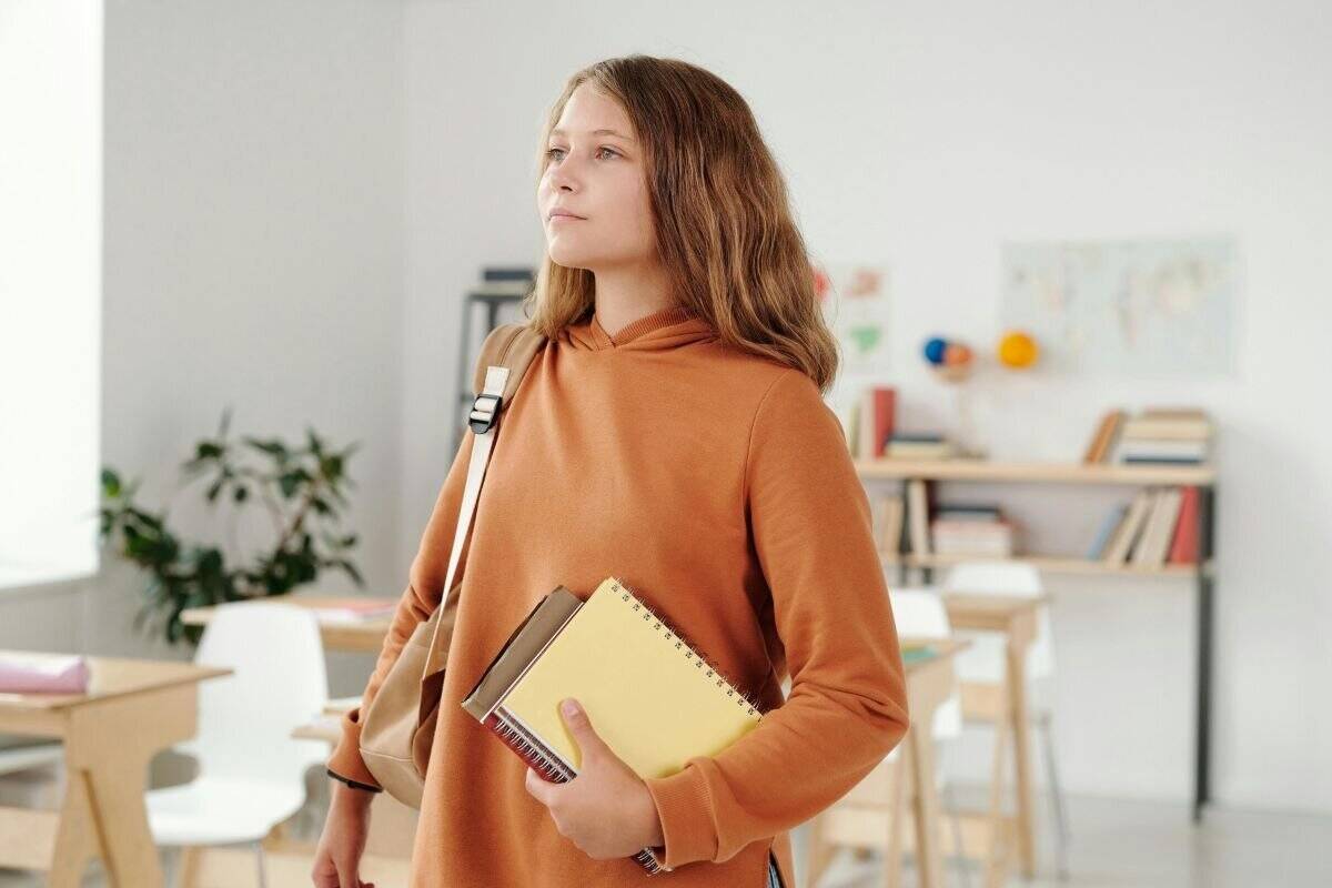 Kvinde i brun sweater bærer bøger