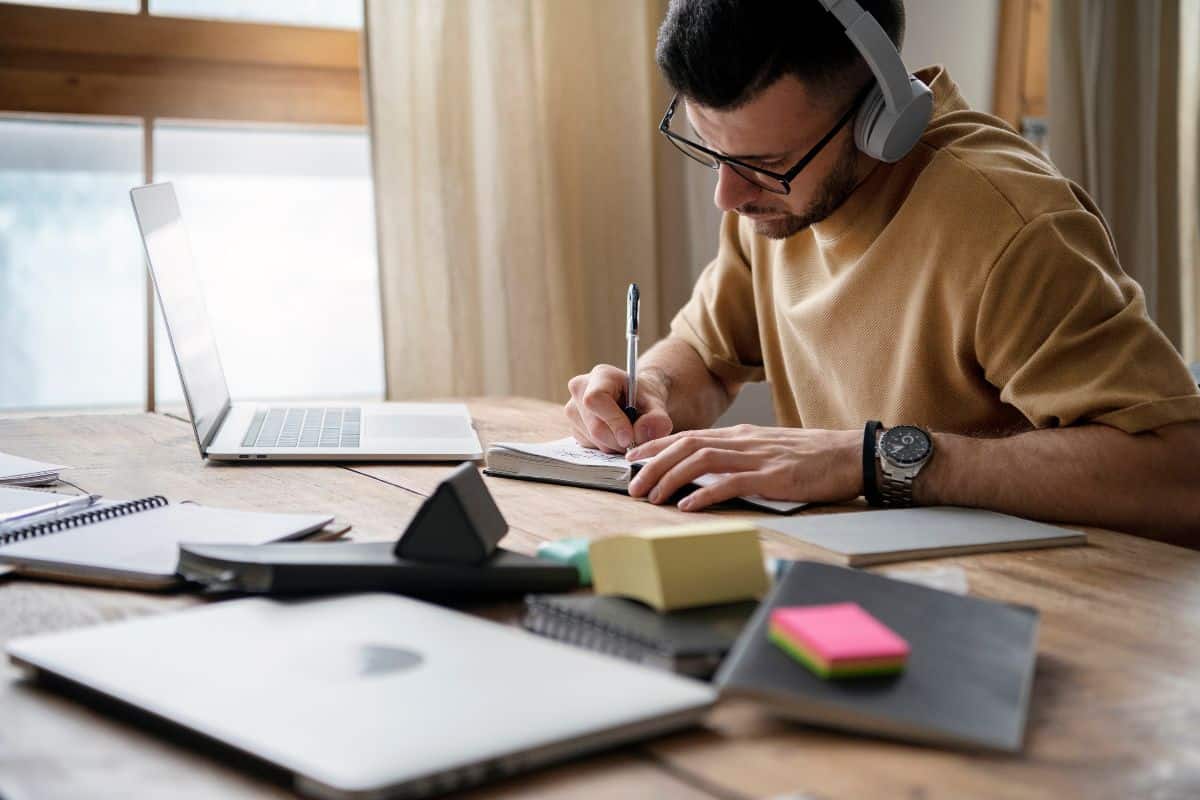 Ung mand skriver på en notesbog under en studiesession