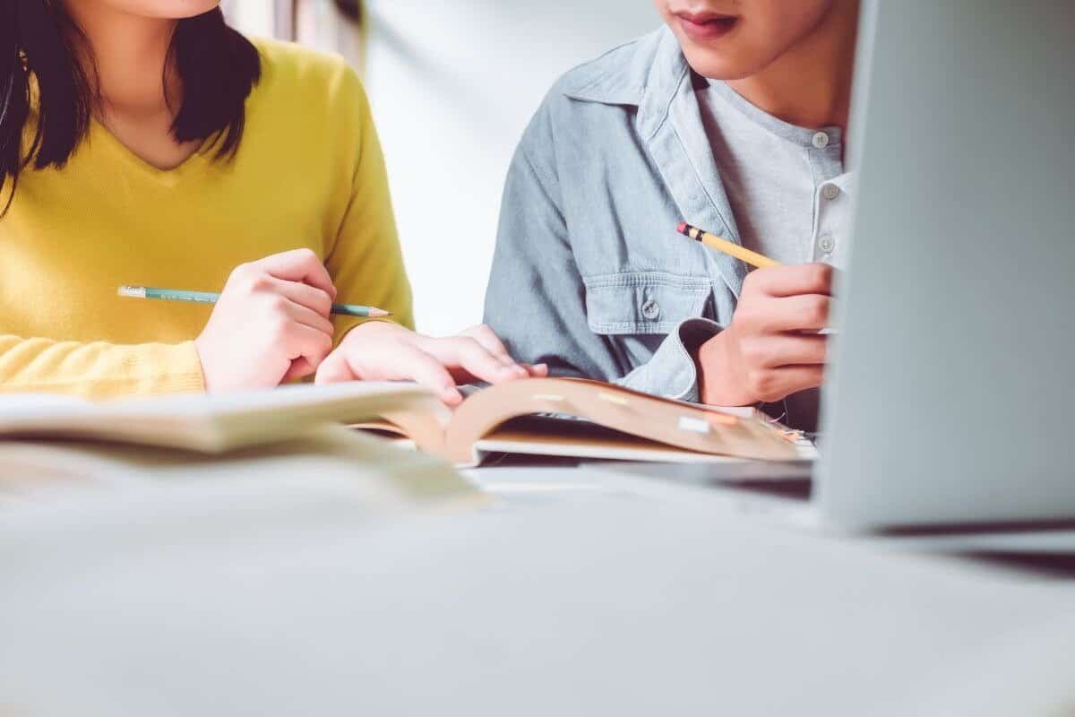 Medium shot of two students studying together using a book