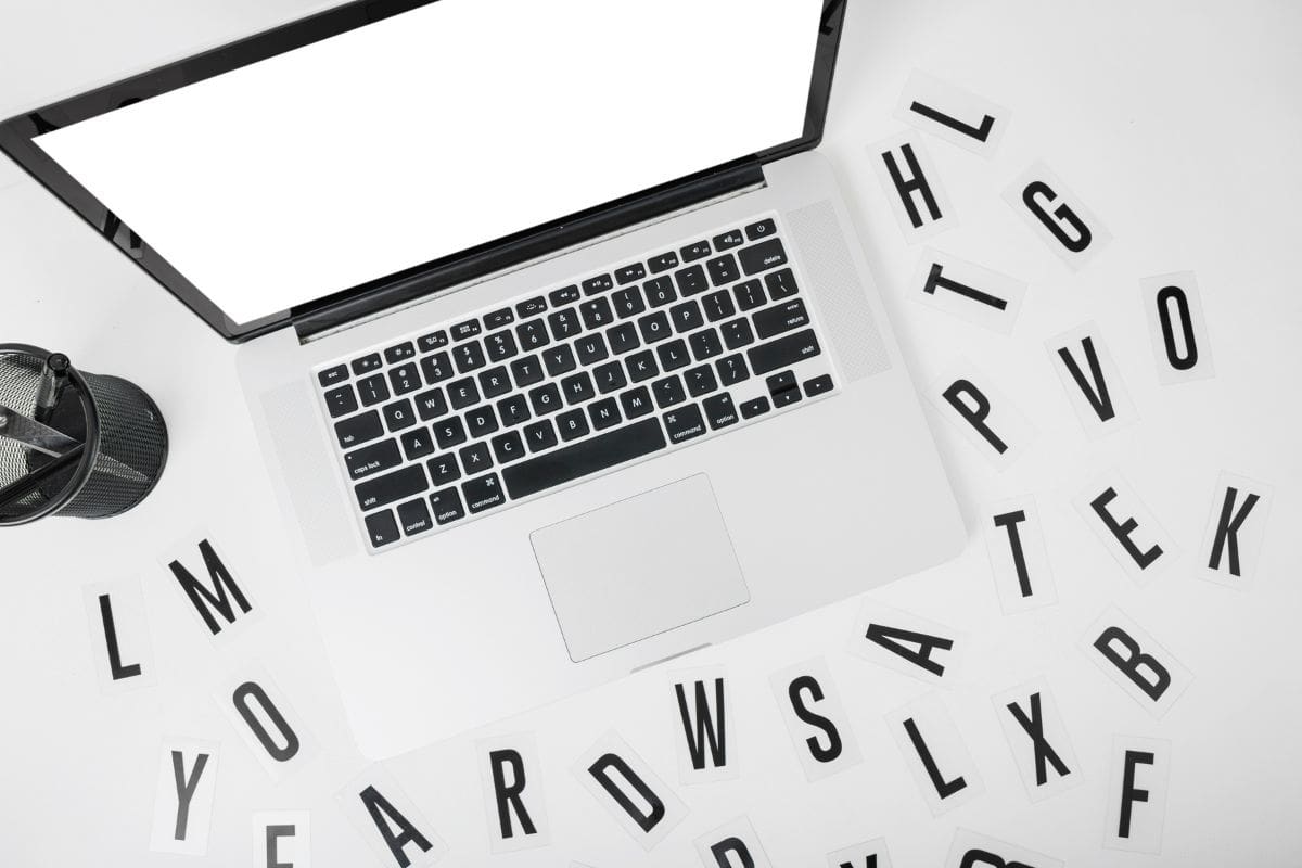 Tampilan laptop yang ditinggikan dengan berbagai huruf pada latar belakang putih