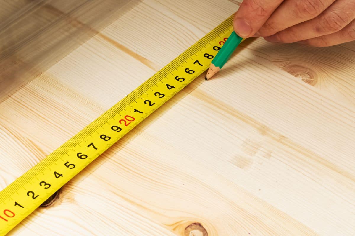 Marking with pencil and ruler on wooden board