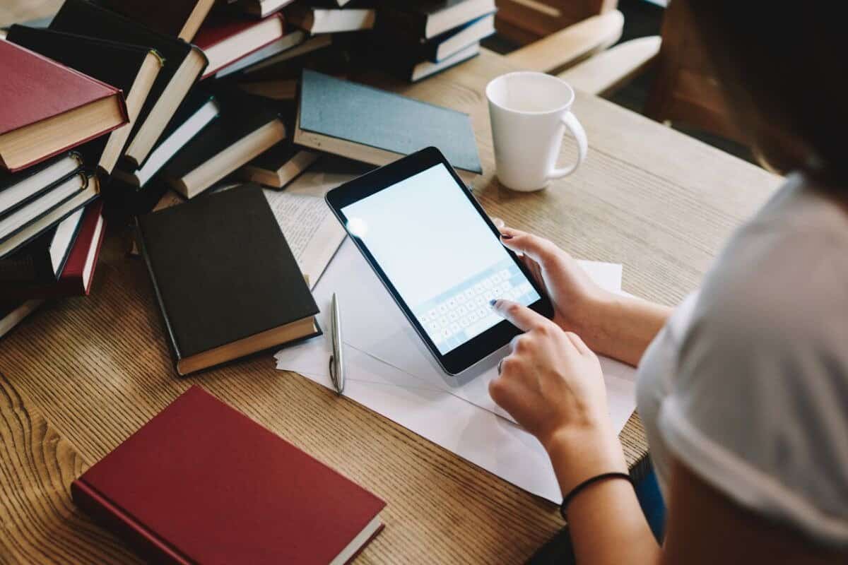 Woman sitting at a desk surrounded by books and a tablet, working