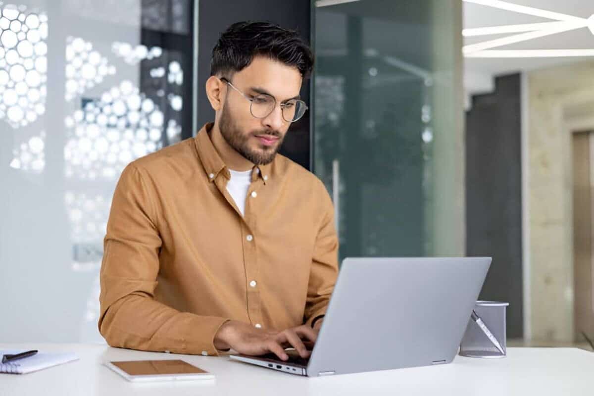 Mand arbejder på sin laptop ved et skrivebord