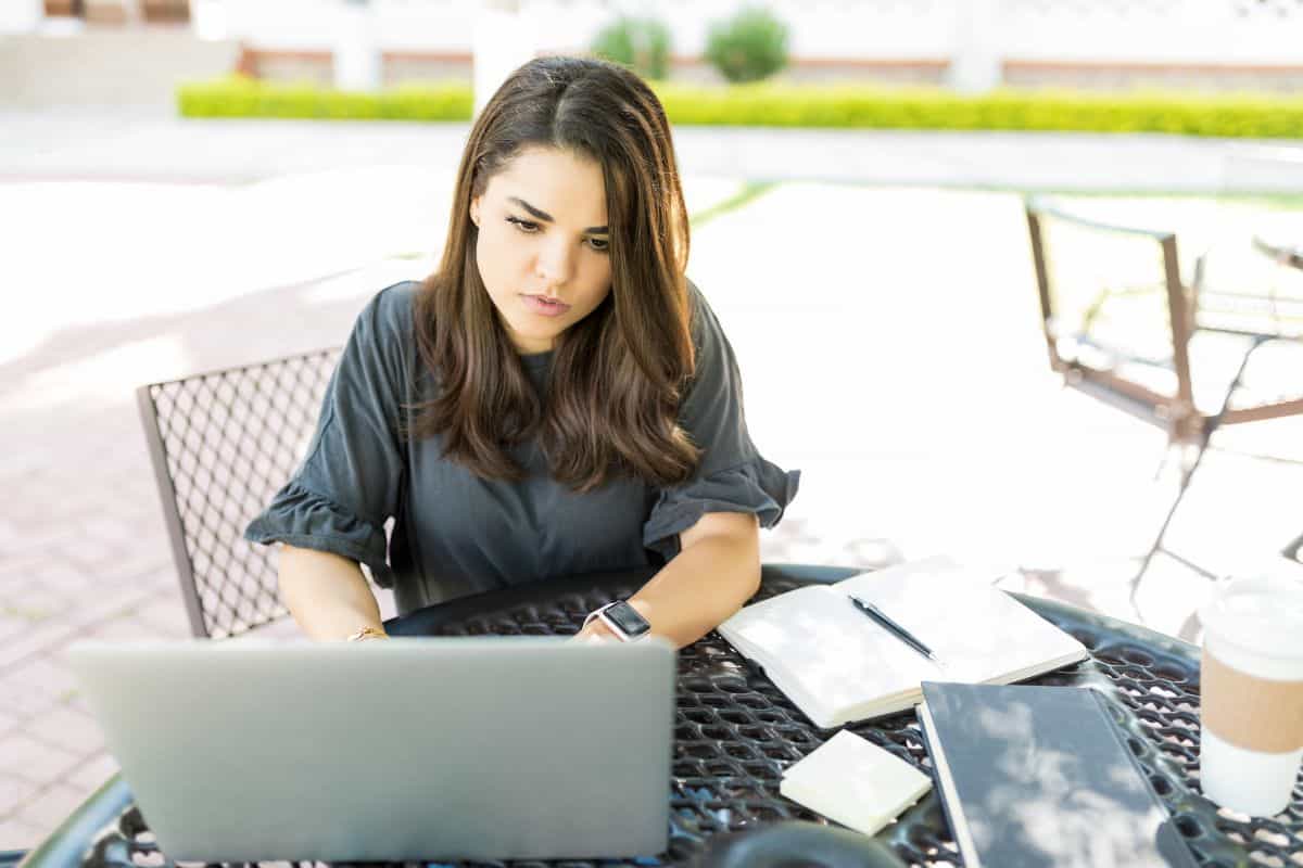 Concentrated mid adult businesswoman using laptop at table in garden