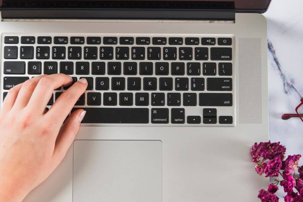 Crop hands using laptop and making notes