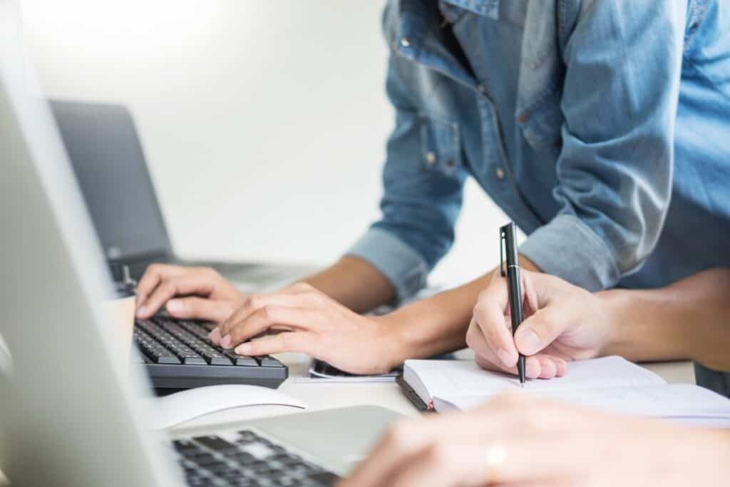 Midsection of colleagues using laptops in office