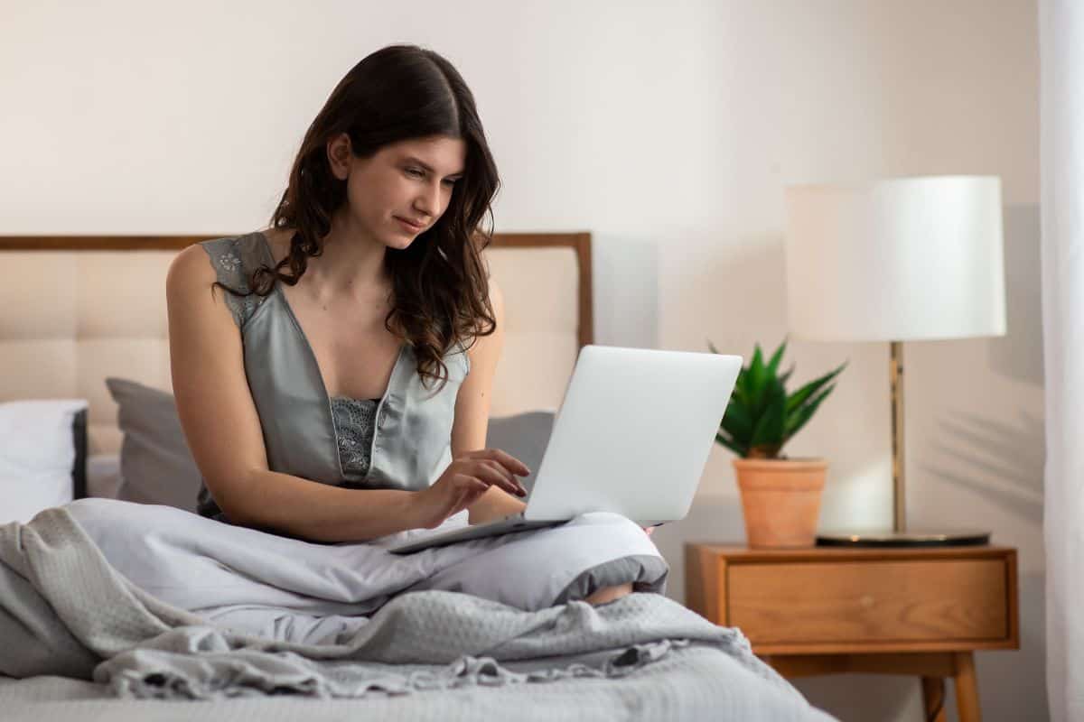 Smiling girl covered with blanket is working with laptop