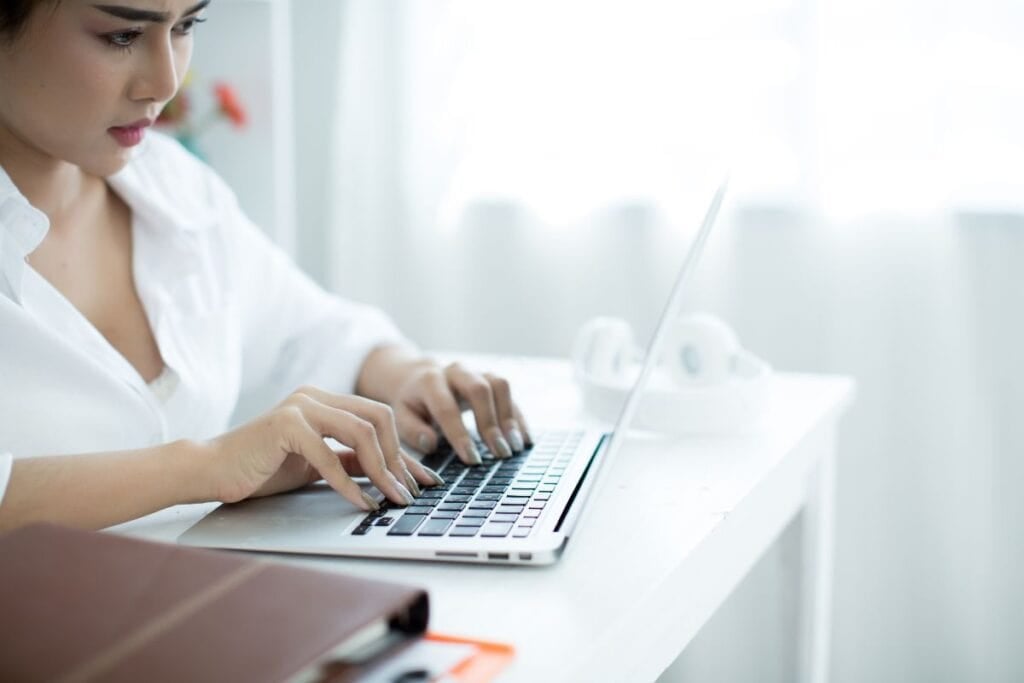 Beautiful young woman working on her laptop in her room