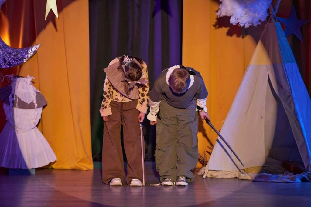 Two kids with swords bowing after play staged in childrens theater