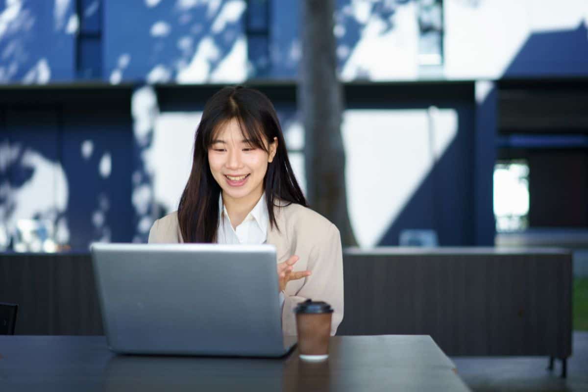 Positive businesswoman sitting on table near office building