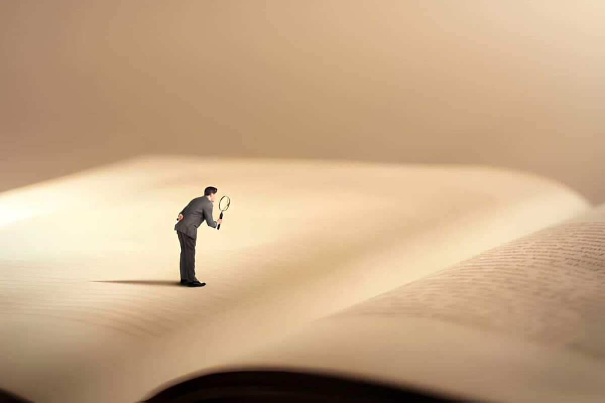 Mini persona leyendo libro con ilustración de lupa”