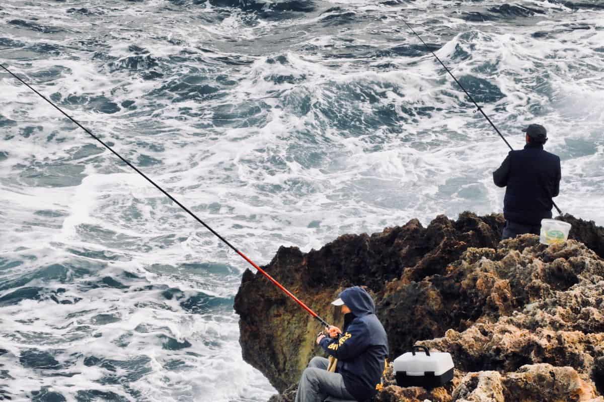 High angle view of people fishing in sea on rocks